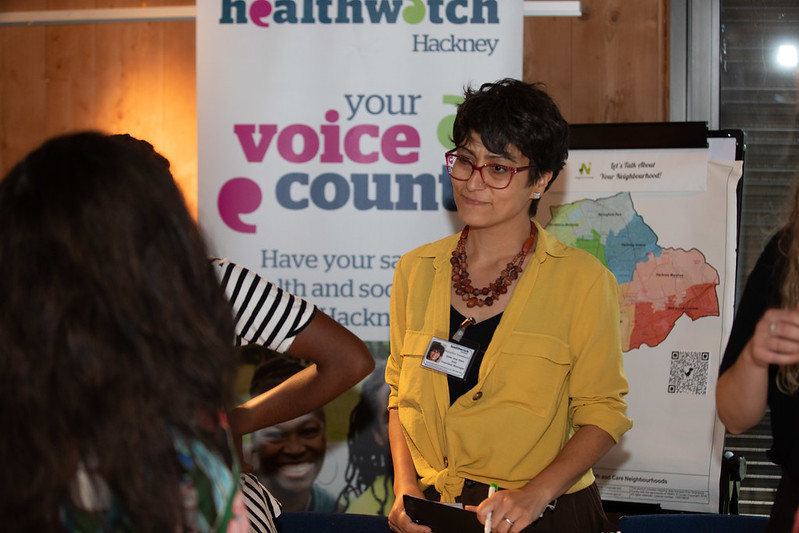 Healthwatch volunteer stood in front of a Healthwatch banner