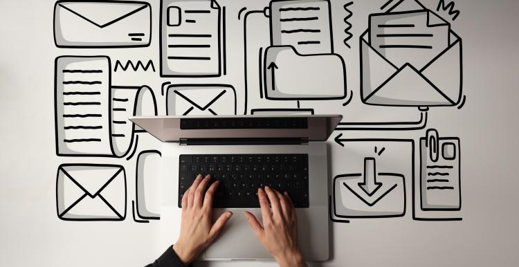 Birdseye view of hands typing on laptop with envelope icons on desk