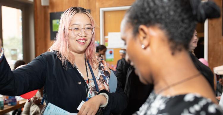 Two people smiling and talking at a Healthwatch event 