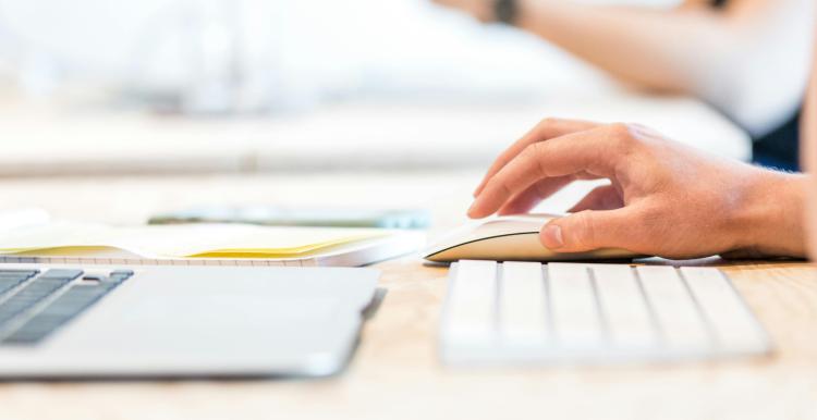 Close up of a laptop keyboard, keyboard and hand on a mouse