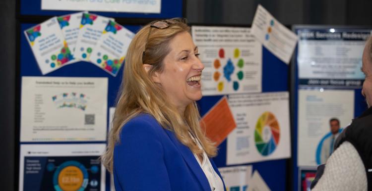 Woman laughing in front of a notice board