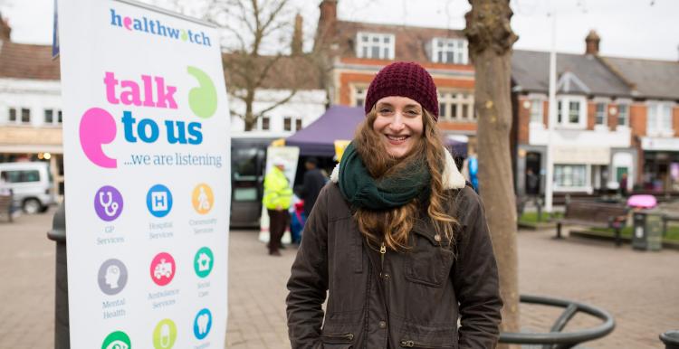 Woman standing next to a Healthwatch banner