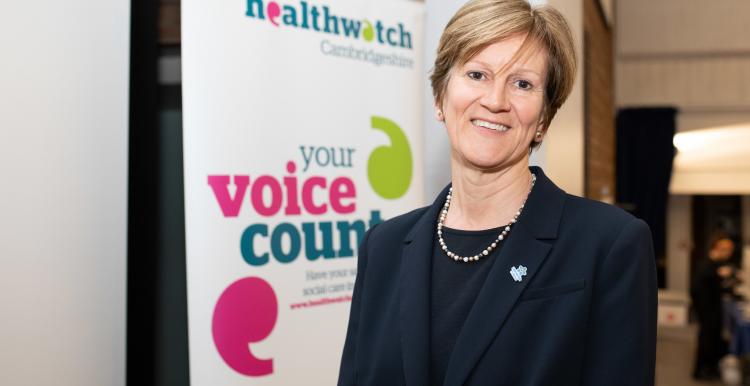 A woman in front of a Healthwatch banner A woman in front of a Healthwatch banner