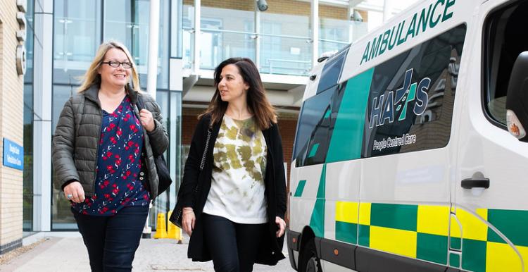 Two women walk away from a hospital building. Two women walk away from a hospital building.