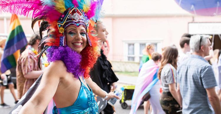 A woman in colourful clothing and feathers at Pride