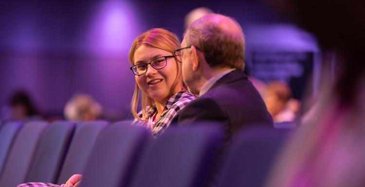 two people talking at a conference two people talking at a conference