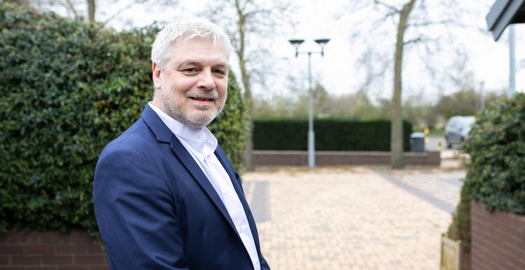 Middle aged man wearing a suit and standing in a courtyard