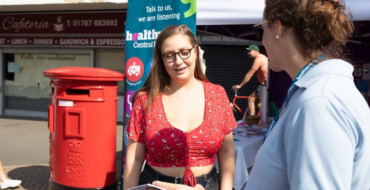 Two people outside at a market talking over a leaflet