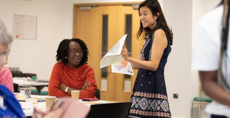 Woman showing some paperwork to a group of people sat around desks