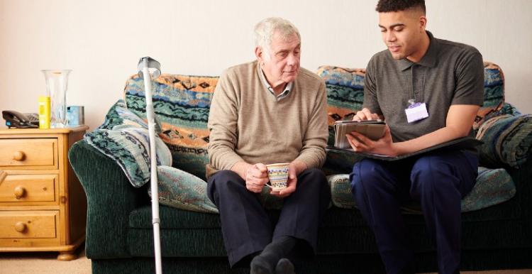 Carer sitting with elderly man on sofa Carer sitting with elderly man on sofa