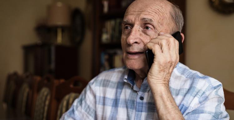 Elderly man resting at home and using mobile phone