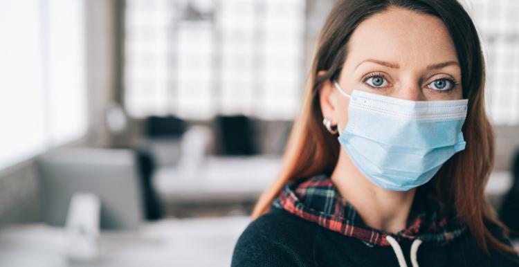 Woman wearing protective face mask in the office for safety and protection during COVID-19