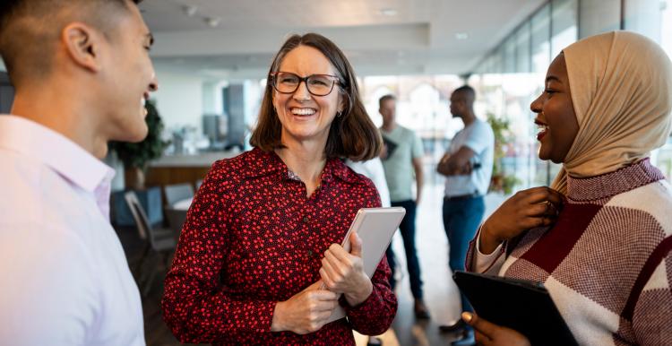 A diverse group of colleagues speak to each other in a modern office space