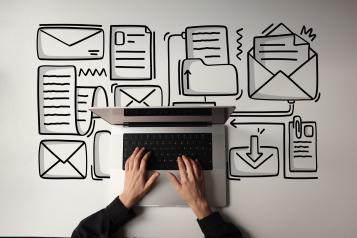 Birdseye view of hands typing on laptop with envelope icons on desk