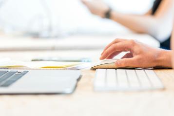 Close up of a laptop keyboard, keyboard and hand on a mouse