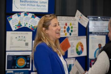 Woman laughing in front of a notice board