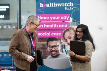 two people in front of a Healthwatch sign 