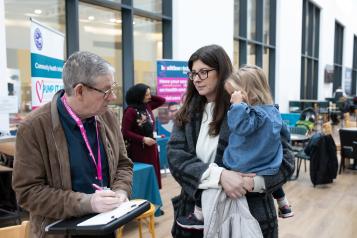 interviewer with notepad speaking with an attendee at an event 
