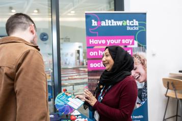 person speaking to Healthwatch representative at event