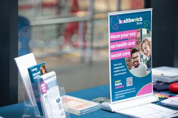 Leaflets and a framed Healthwatch poster on a table 