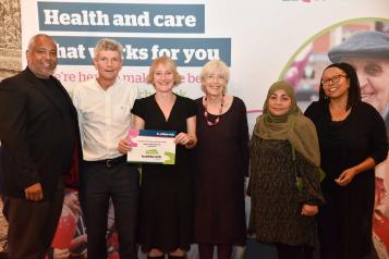 group of people in front of a Healthwatch background