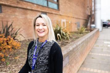 Woman with blonder hair standing outside. Wearing a lanyard with Healthwatch on it.