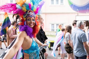 A woman in colourful clothing and feathers at Pride