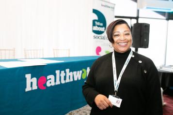 Female volunteer standing in front of a Healthwatch tablecloth