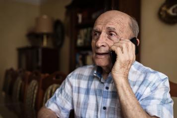 Elderly man resting at home and using mobile phone