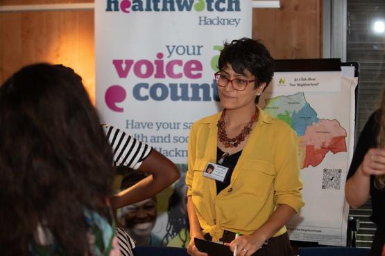 Healthwatch volunteer stood in front of a Healthwatch banner