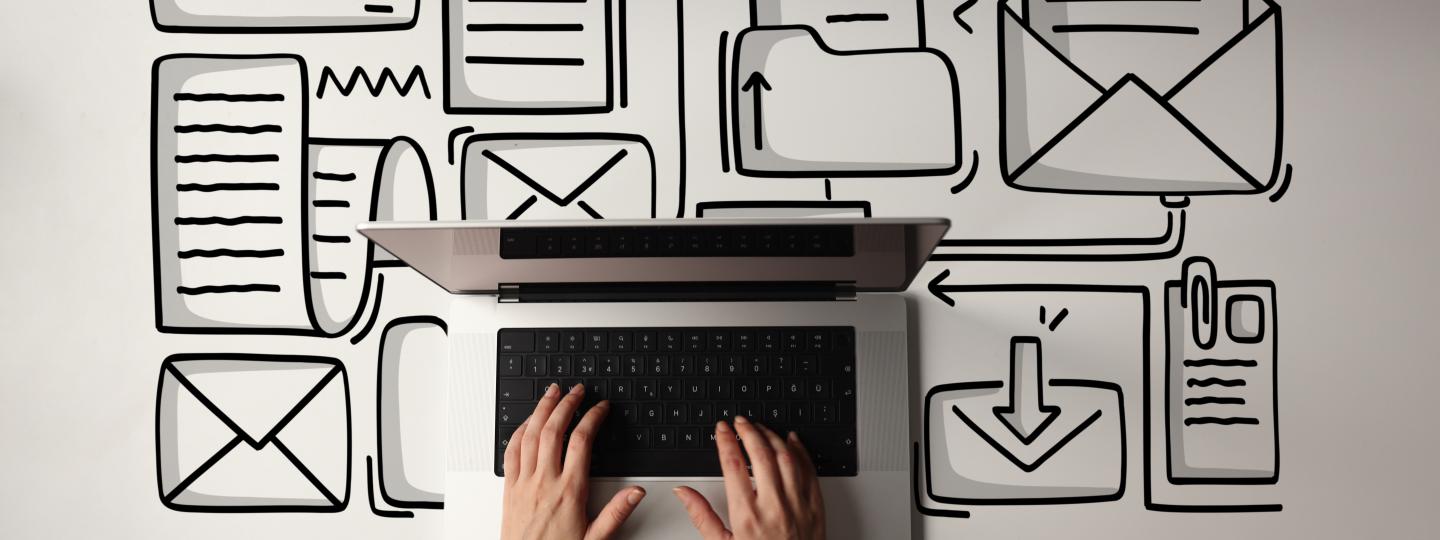 Birdseye view of hands typing on laptop with envelope icons on desk