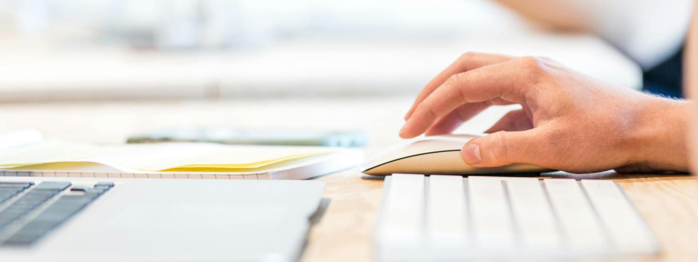 Close up of a laptop keyboard, keyboard and hand on a mouse