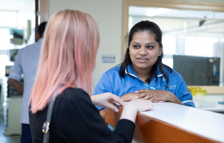 A female nurse talking to a patient in a hospital setting
