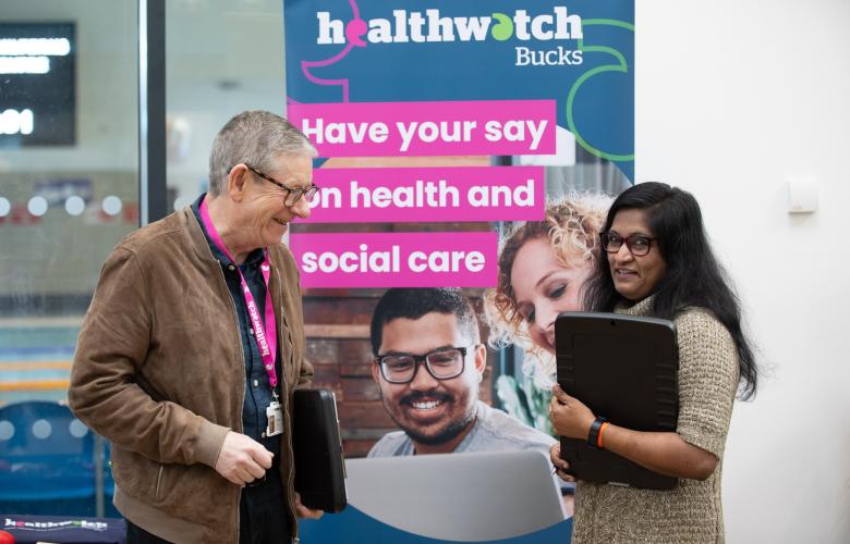 two people in front of a Healthwatch sign 
